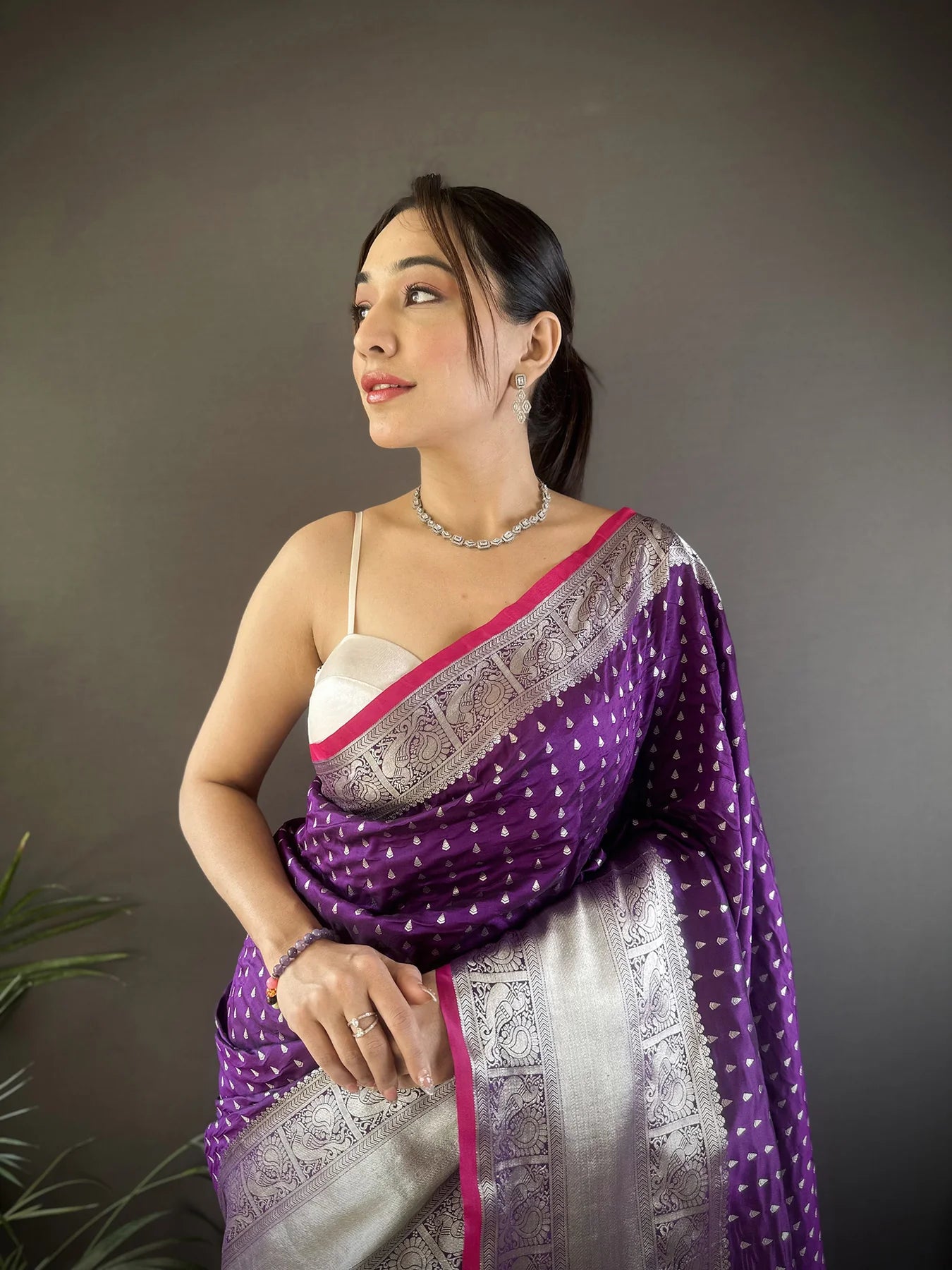 Elegant woman wearing a traditional purple Banarasi silk saree with intricate gold zari work, perfect for weddings and festive occasions.