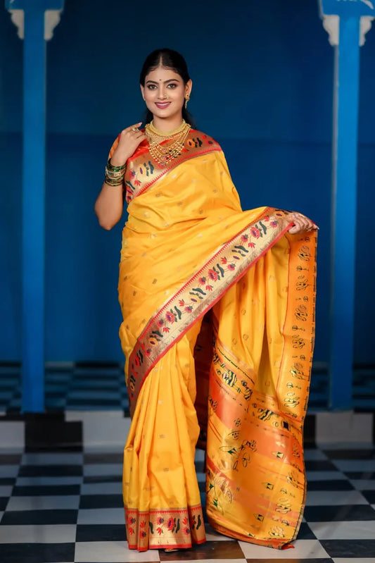 Traditional paithani saree look in bright yellow silk with orange-red border, colorful floral motifs, styled with layered gold jewelry