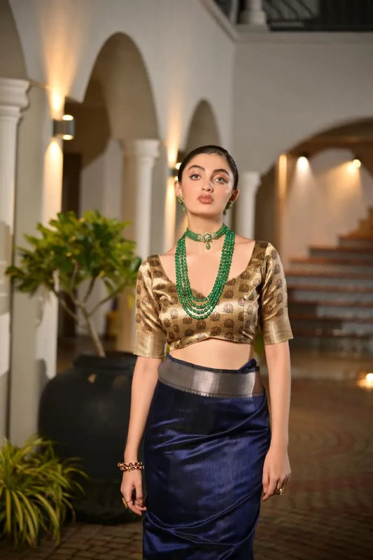 Navy blue tussar silk saree with golden zari border and ornate brocade pallu displayed on model in elegant colonial architecture setting