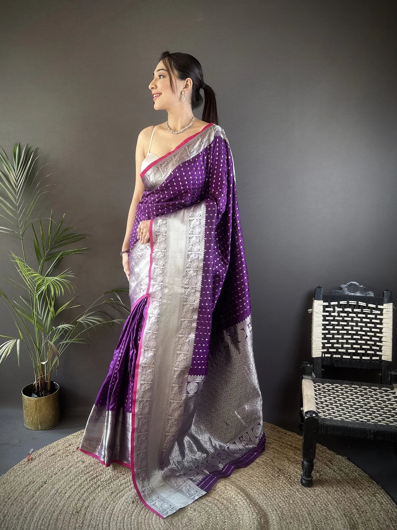 Elegant woman wearing a traditional purple Banarasi silk saree with intricate gold zari work, perfect for weddings and festive occasions.