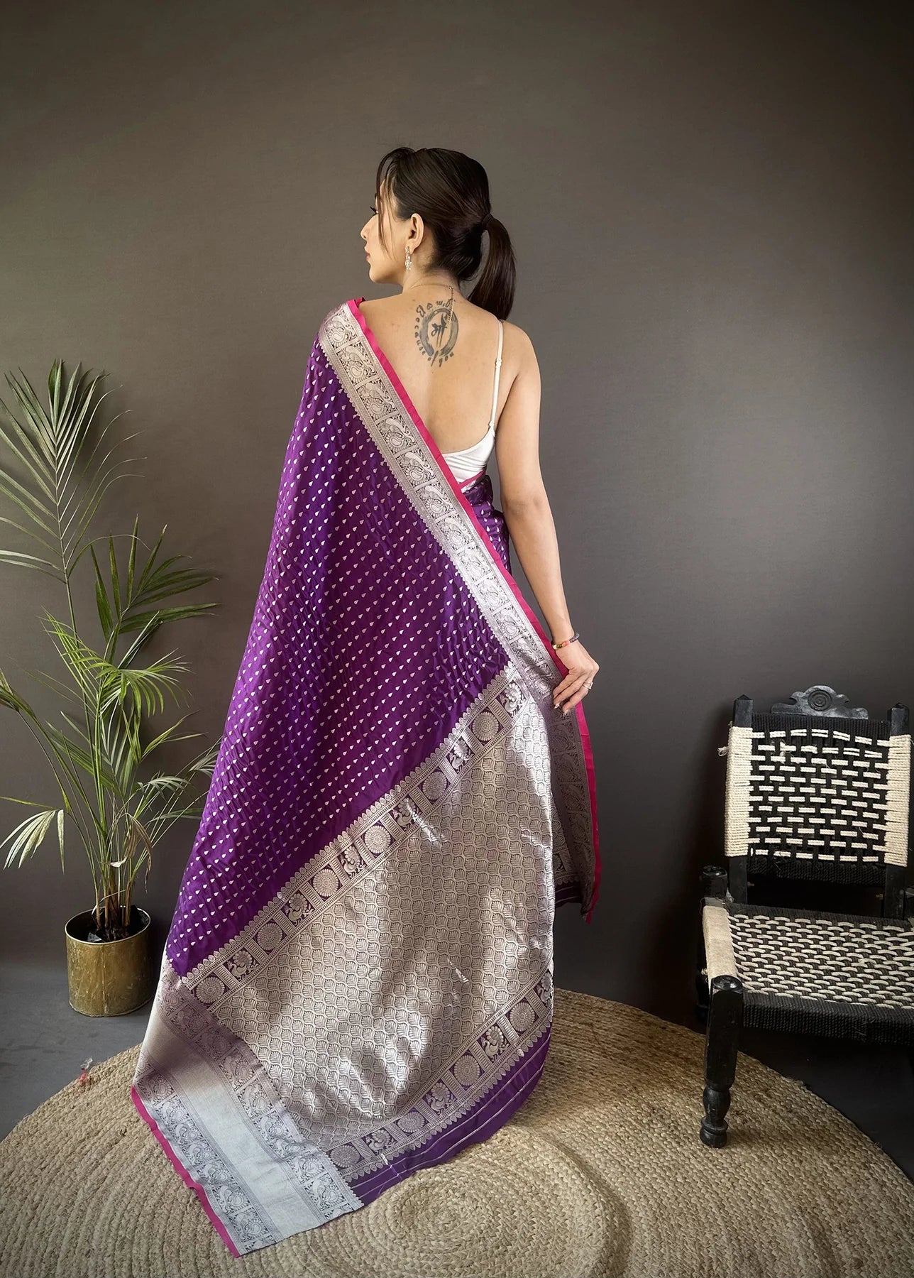 Elegant woman wearing a traditional purple Banarasi silk saree with intricate gold zari work, perfect for weddings and festive occasions.
