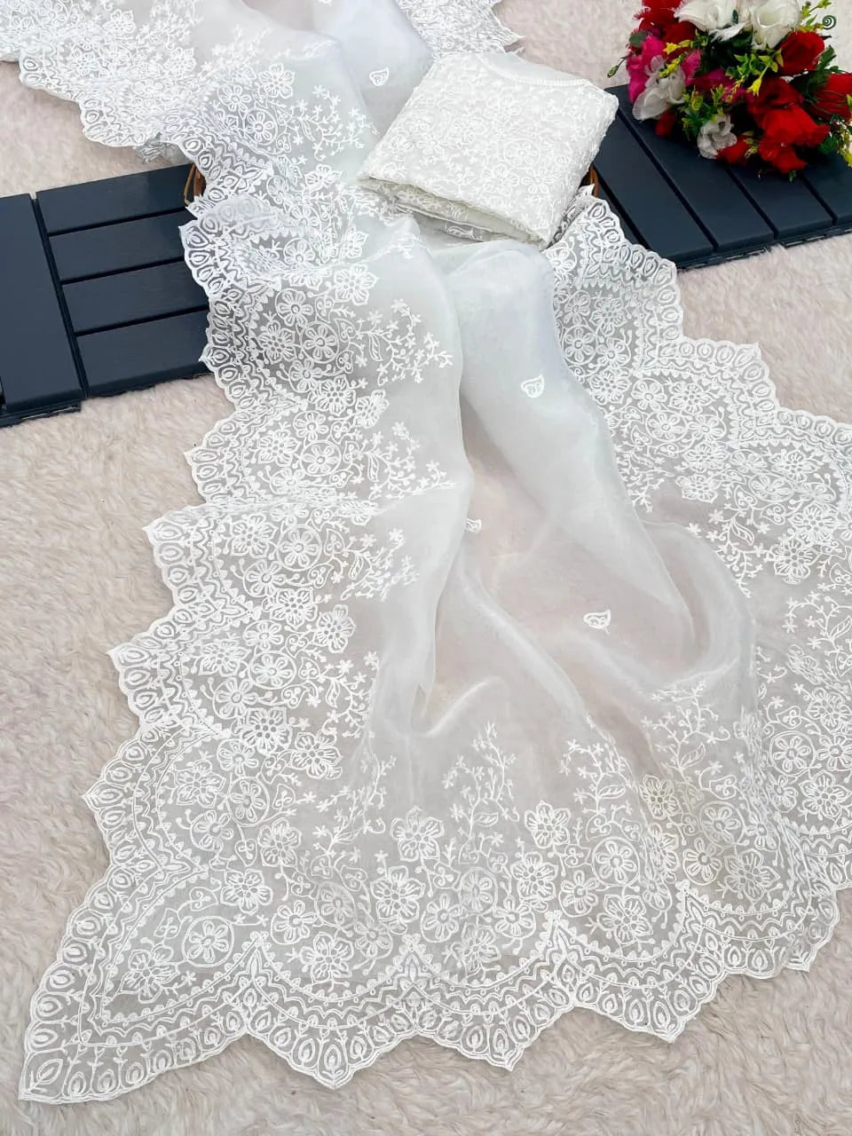 White organza saree with sleeveless embroidered blouse design featuring intricate lace border and minimal studio backdrop