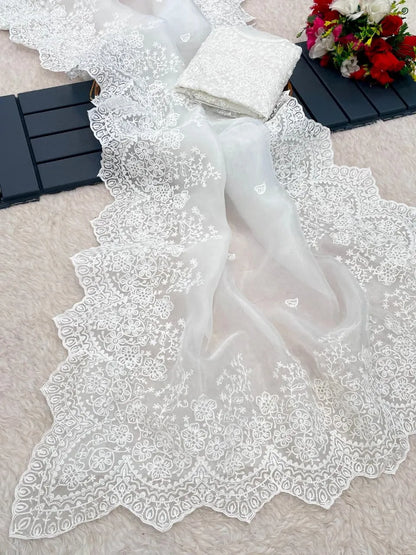 White organza saree with sleeveless embroidered blouse design featuring intricate lace border and minimal studio backdrop