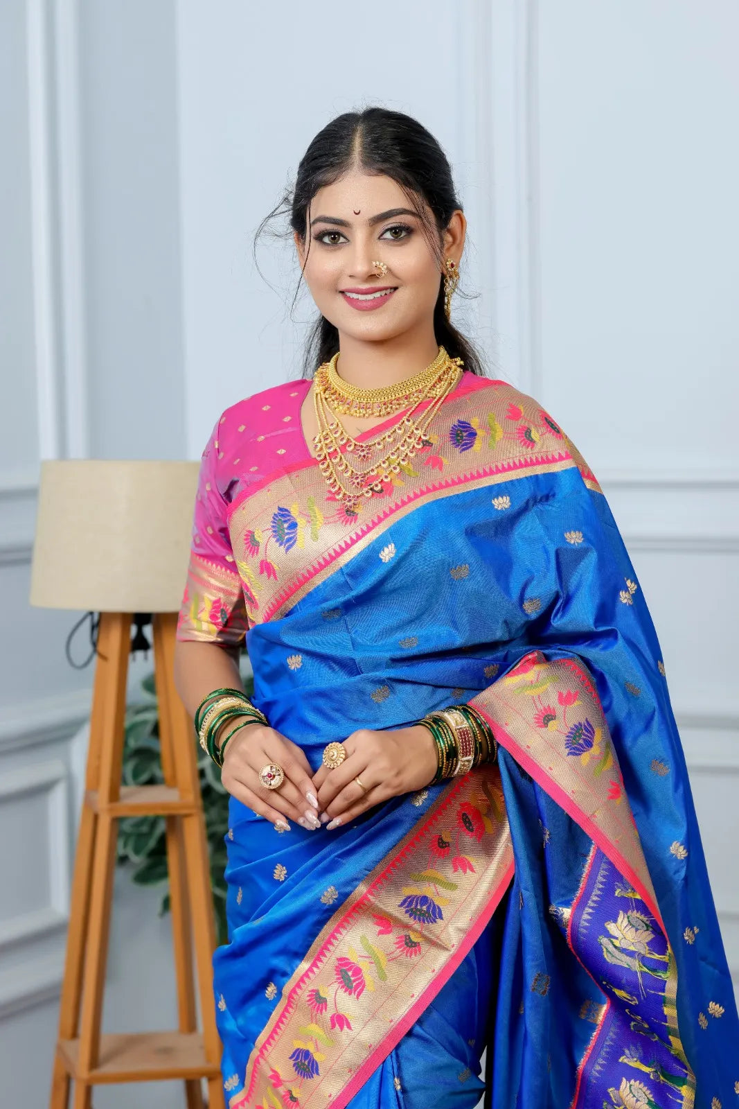Woman wearing royal blue Paithani saree with golden zari border and pink blouse in traditional Indian style