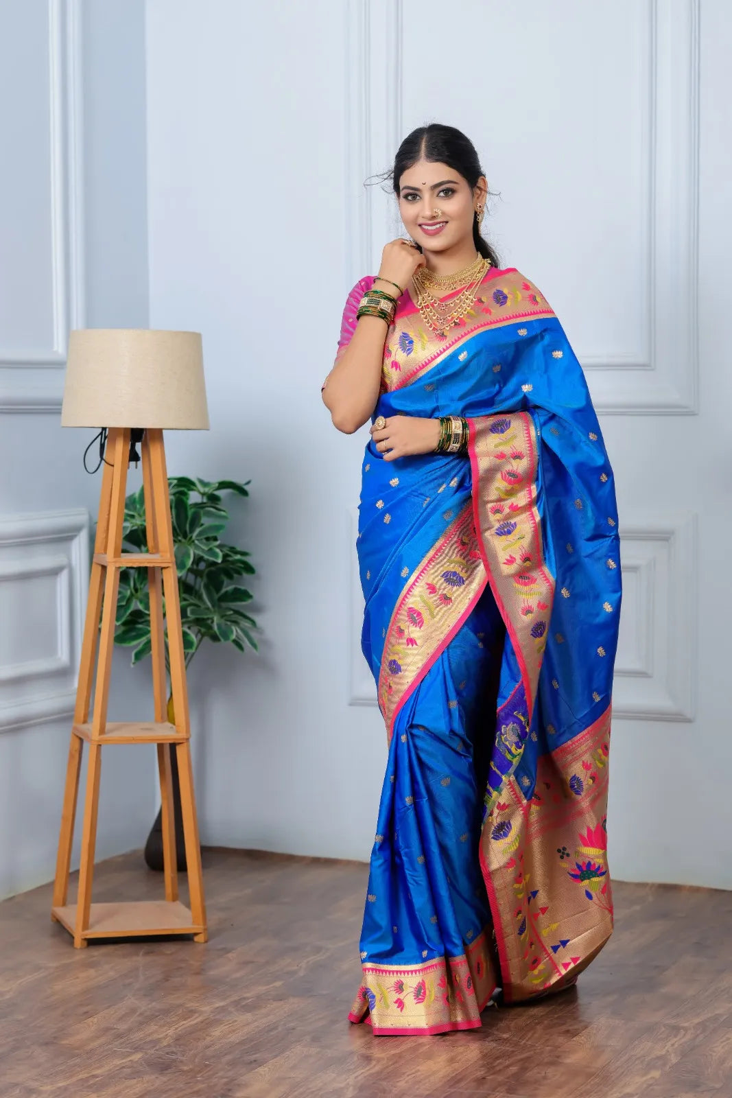 Woman wearing royal blue Paithani saree with golden zari border and pink blouse in traditional Indian style