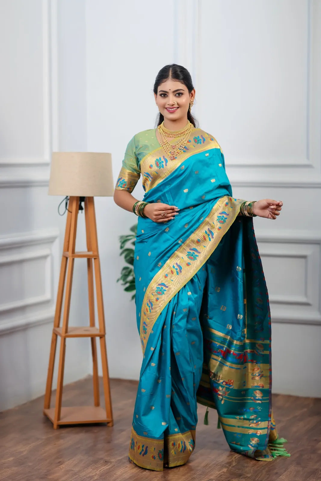 Traditional paithani saree look featuring peacock blue silk saree with golden zari border and colorful peacock motifs styled with gold jewelry