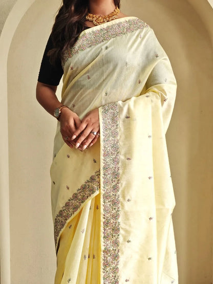 Woman wearing pastel yellow tussar silk saree with embroidered floral border and black blouse accessorized with gold choker necklace