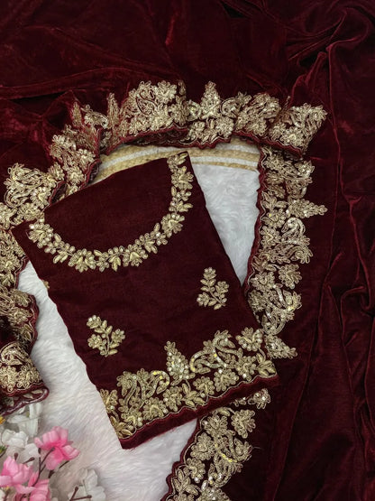 Maroon velvet celebrity style wedding saree featuring intricate gold zari work on borders and embellished three-quarter sleeve blouse