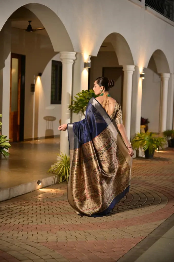 Navy blue tussar silk saree with golden zari border and ornate brocade pallu displayed on model in elegant colonial architecture setting
