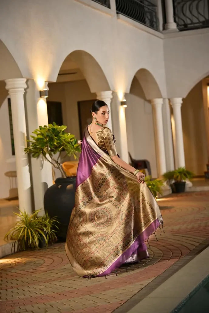 Purple tussar silk saree with golden border and ornate pallu displayed on model in traditional architectural setting with white pillars and arches