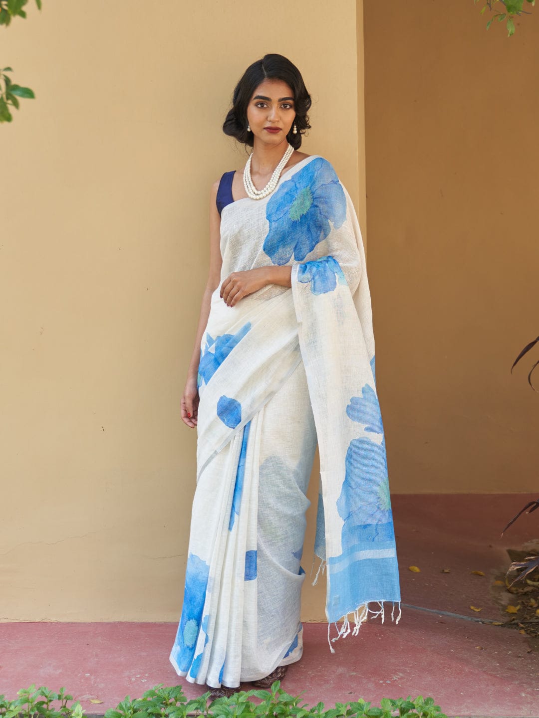 Elegant woman draped in a white linen digital print saree with blue floral design